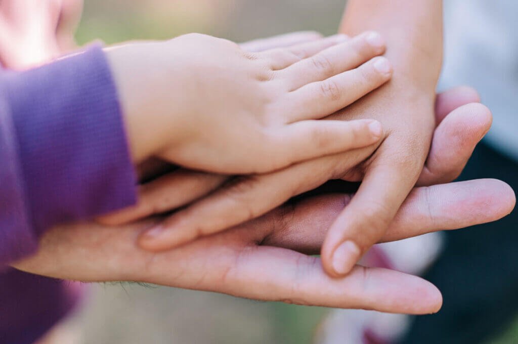 Children's hands stacked on adult hand