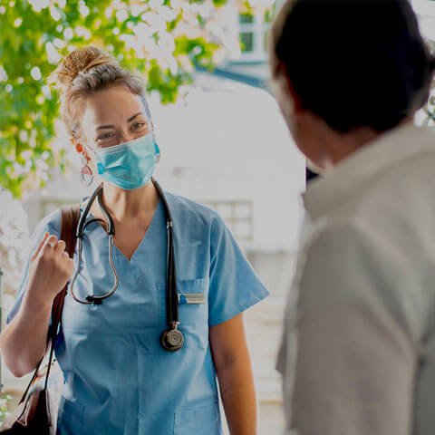 Health worker standing at the front door and person welcoming them in