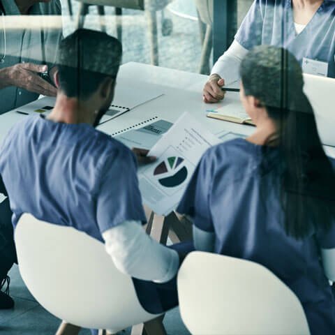 Group of healthcare workers sat round a table talking